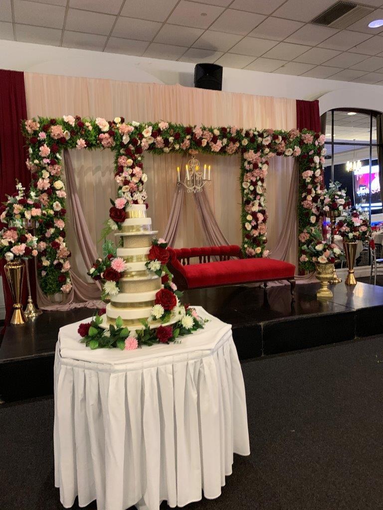 Tiered wedding cake in front of a floral backdrop